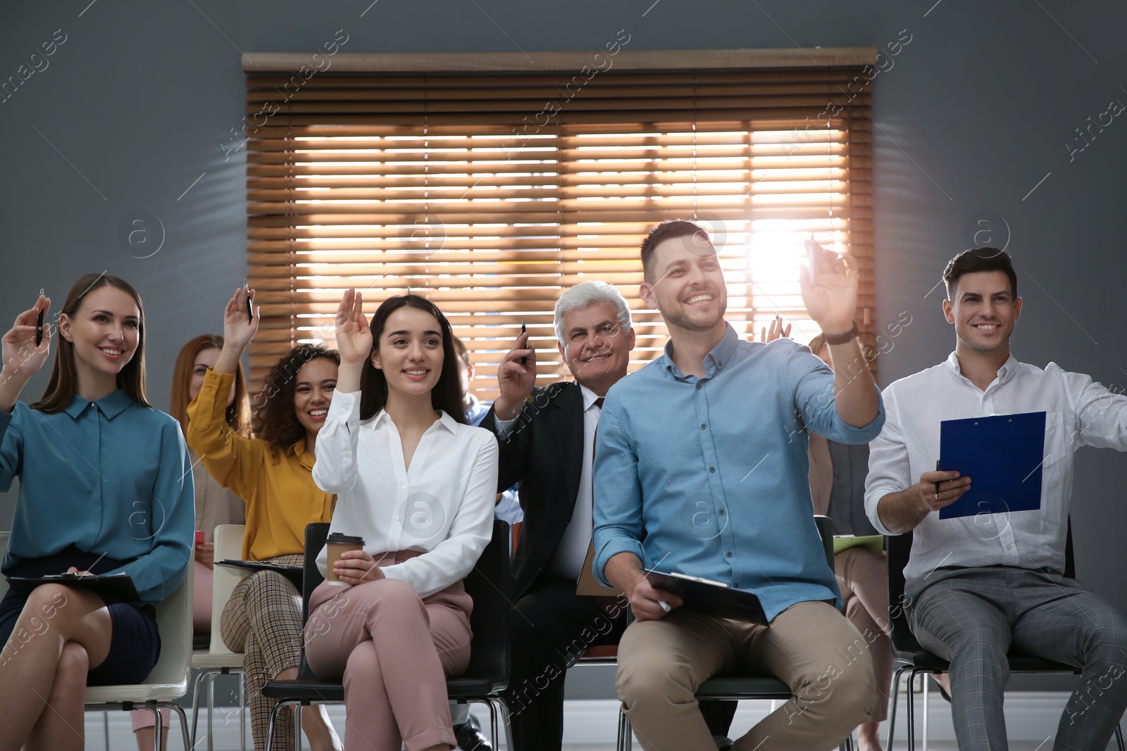 Photo of People raising hands to ask questions at seminar in office