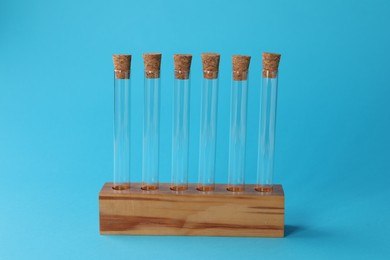 Test tubes in wooden stand on light blue background. Laboratory glassware