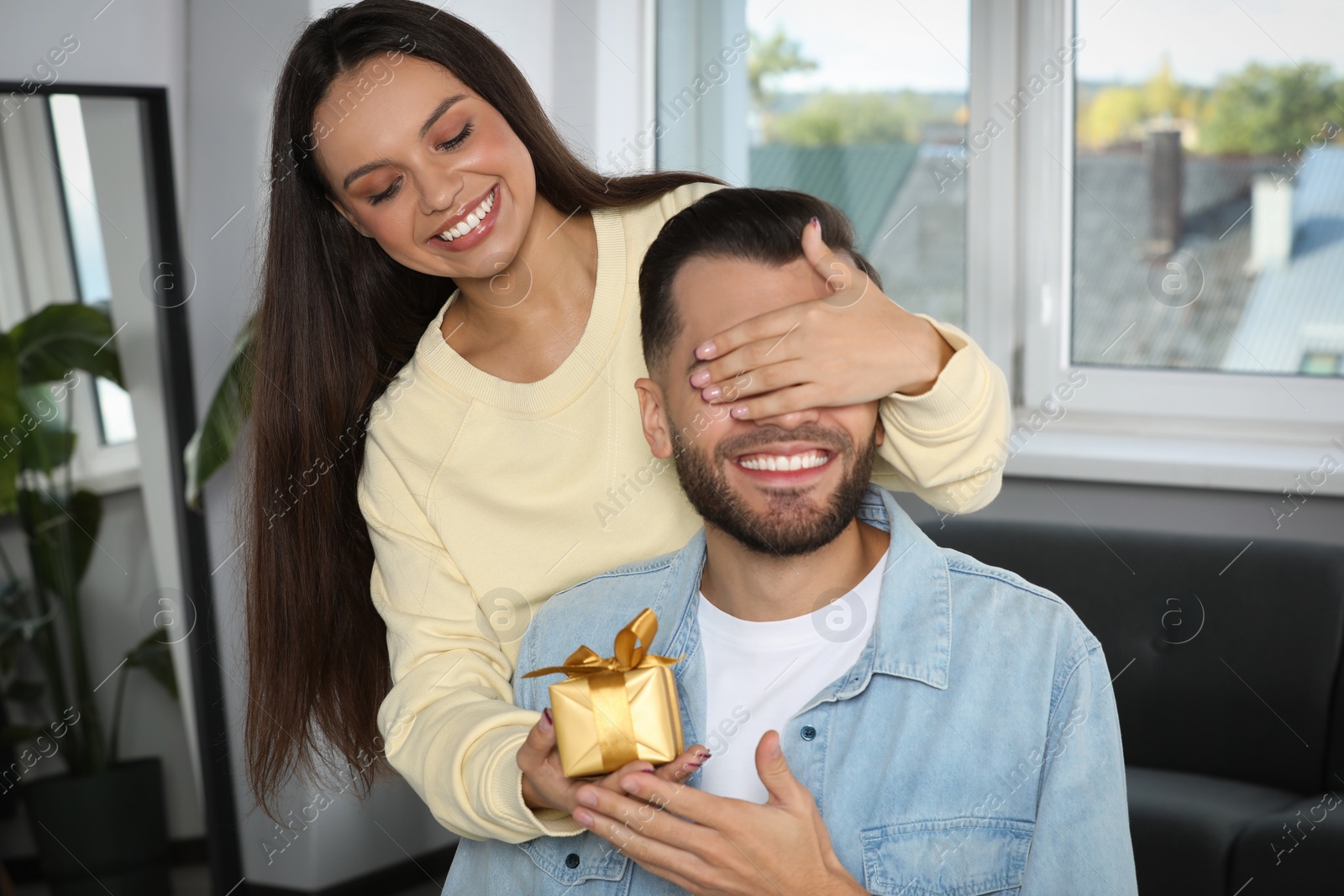 Photo of Woman presenting gift to her boyfriend at home