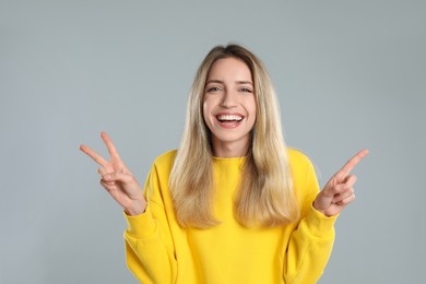 Woman showing number three with her hands on light grey background