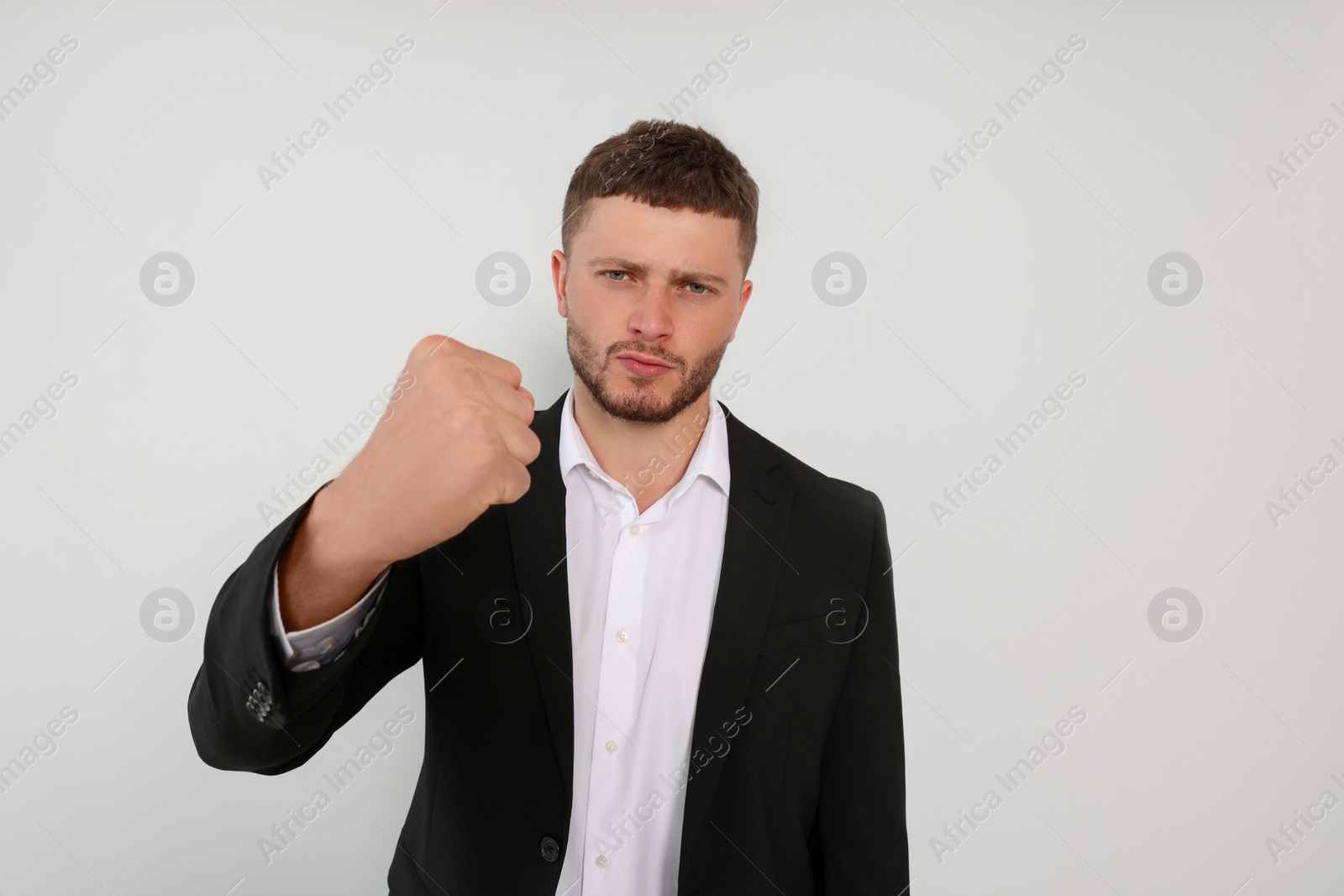Photo of Aggressive young man showing fist on white background