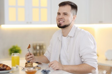 Smiling man having tasty breakfast at home