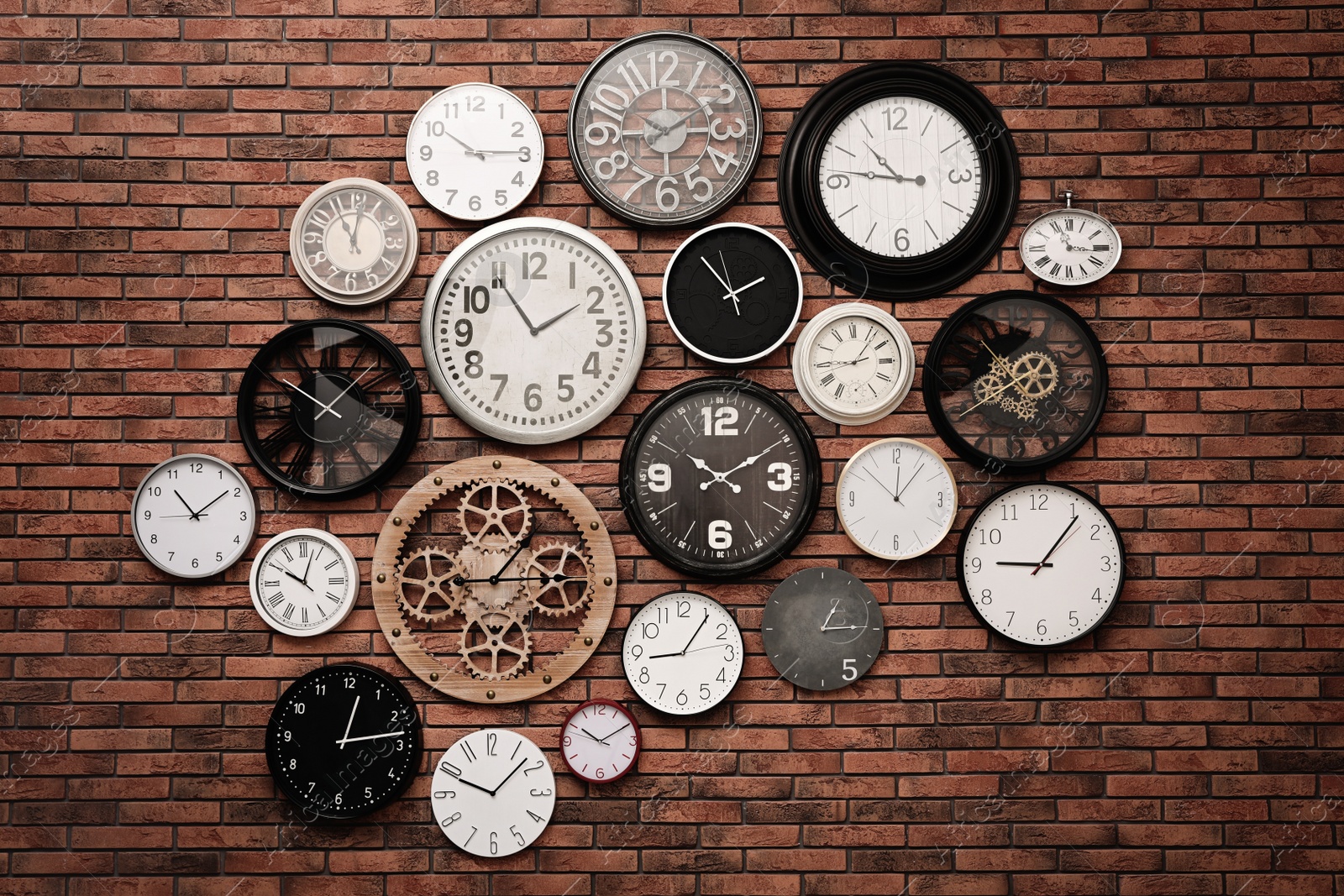 Photo of Collection of clocks hanging on red brick wall