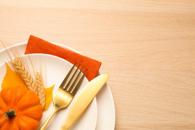 Photo of Top view of seasonal table setting with autumn leaves, pumpkin and wheat spikes on wooden background, space for text. Thanksgiving Day