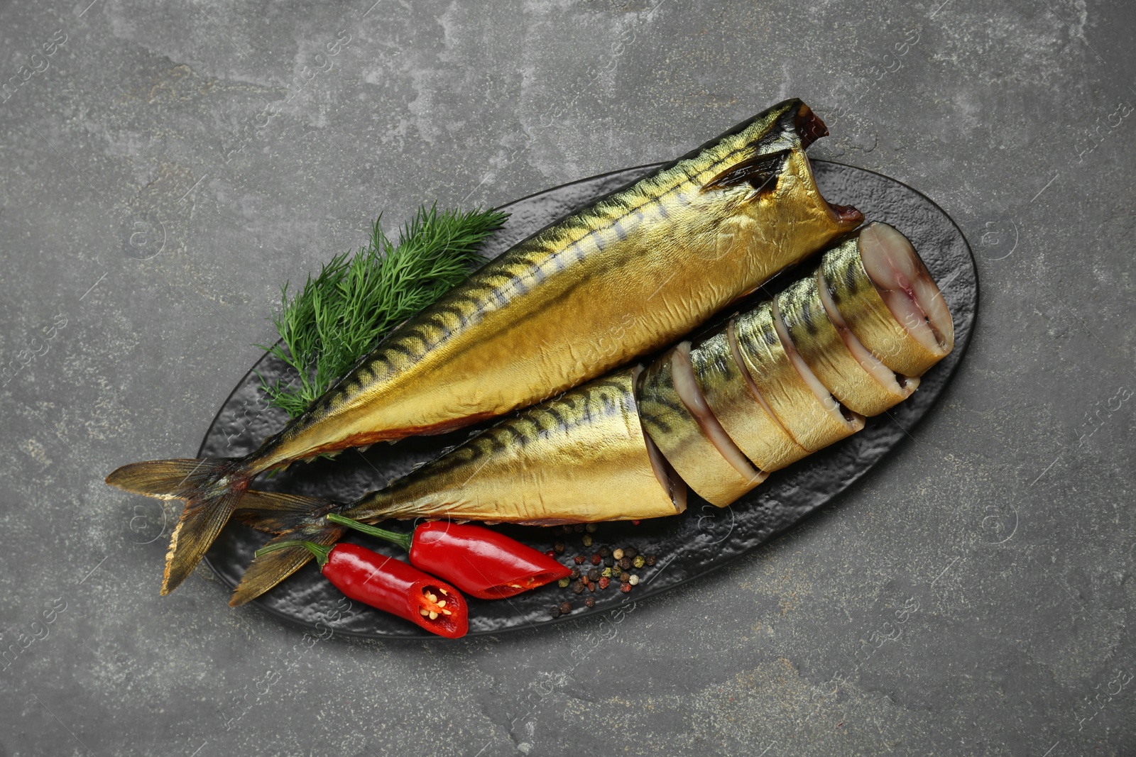 Photo of Delicious smoked mackerels with pepper, dill and spices on dark grey table, top view