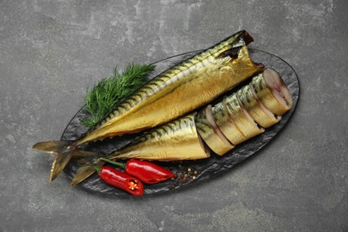 Delicious smoked mackerels with pepper, dill and spices on dark grey table, top view