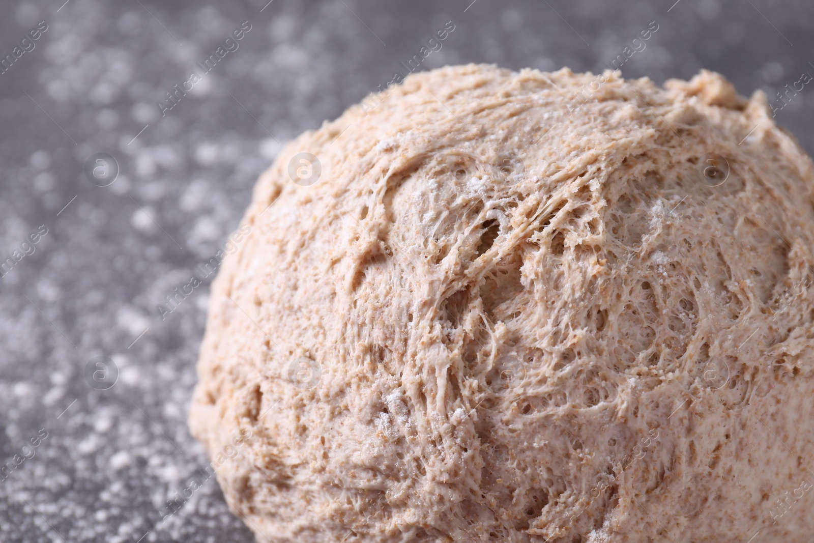 Photo of Fresh sourdough and flour on grey table, closeup