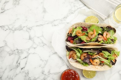 Delicious tacos with shrimps, lime and sauce on white marble table, flat lay. Space for text