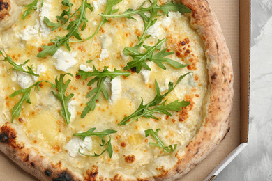 Photo of Delicious cheese pizza with arugula in takeout box, closeup
