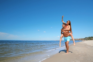Photo of Beautiful woman and her boyfriend on beach, space for text. Happy couple