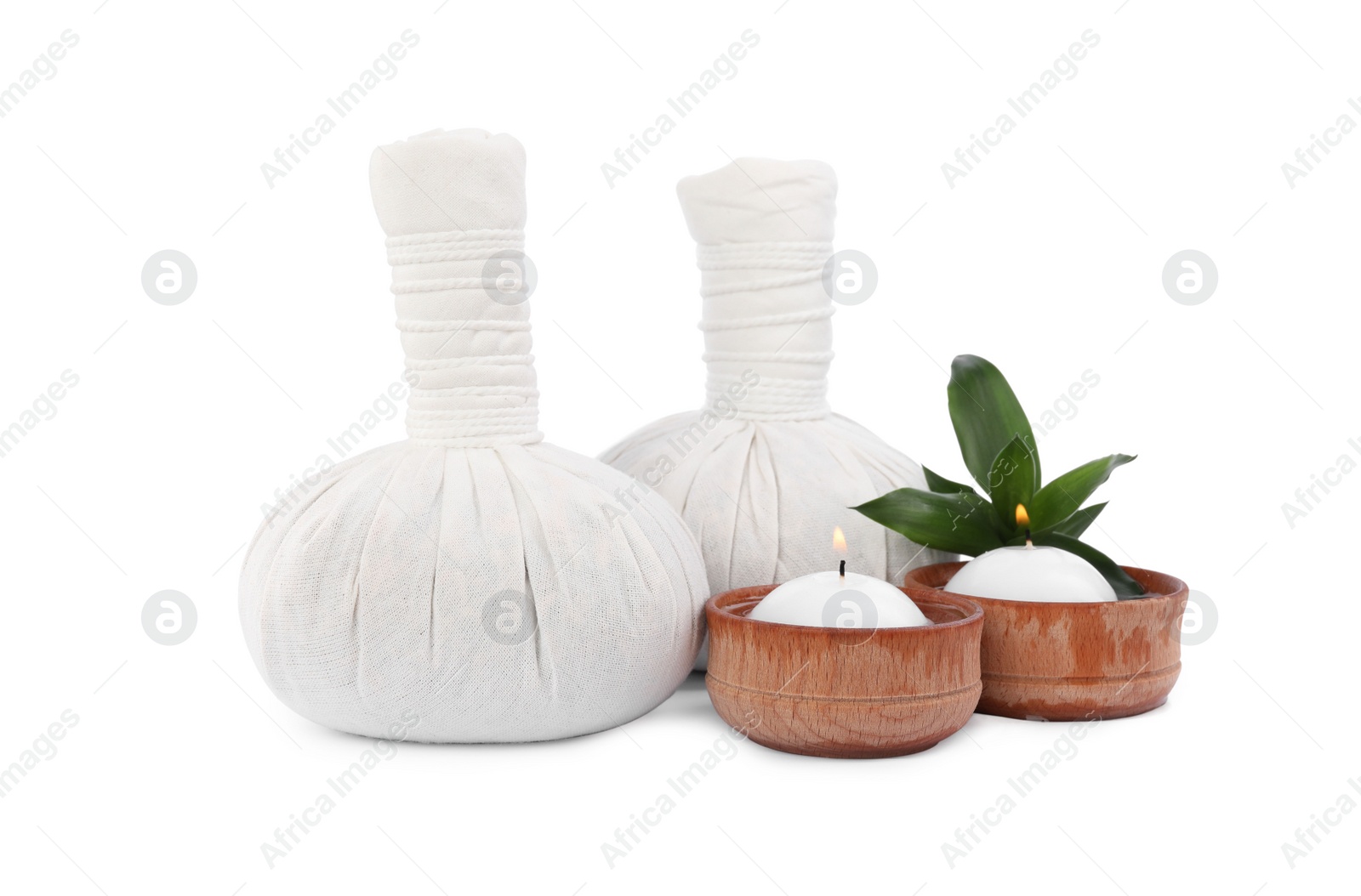 Photo of Herbal massage bags, green plant and candles on white background. Spa supply