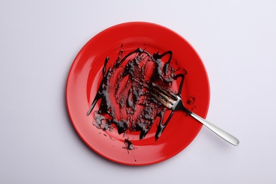 Photo of Dirty plate with food leftovers and fork on white background, top view