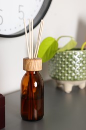 Photo of Aromatic reed air freshener near houseplant on gray table indoors