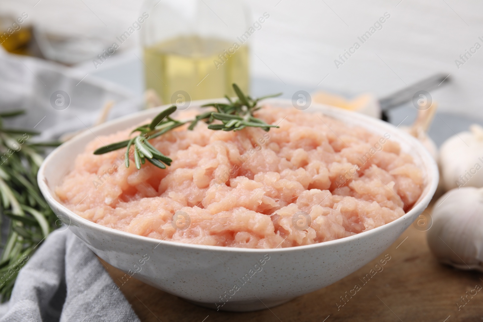 Photo of Fresh raw minced meat and rosemary in bowl on table, closeup