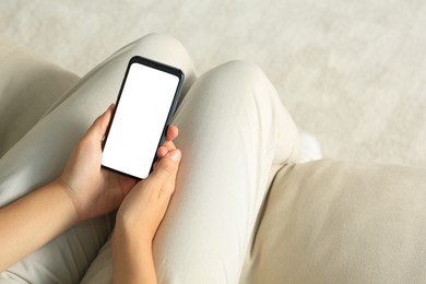 Photo of Young woman with smartphone on sofa indoors, closeup