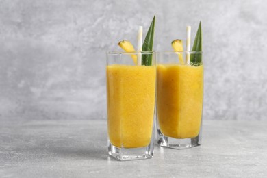 Tasty pineapple smoothie on light gray table