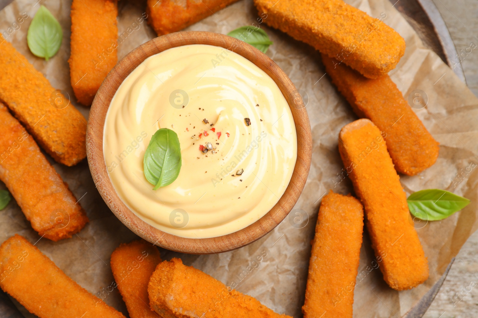 Photo of Delicious chicken nuggets and cheese sauce with basil on table, top view