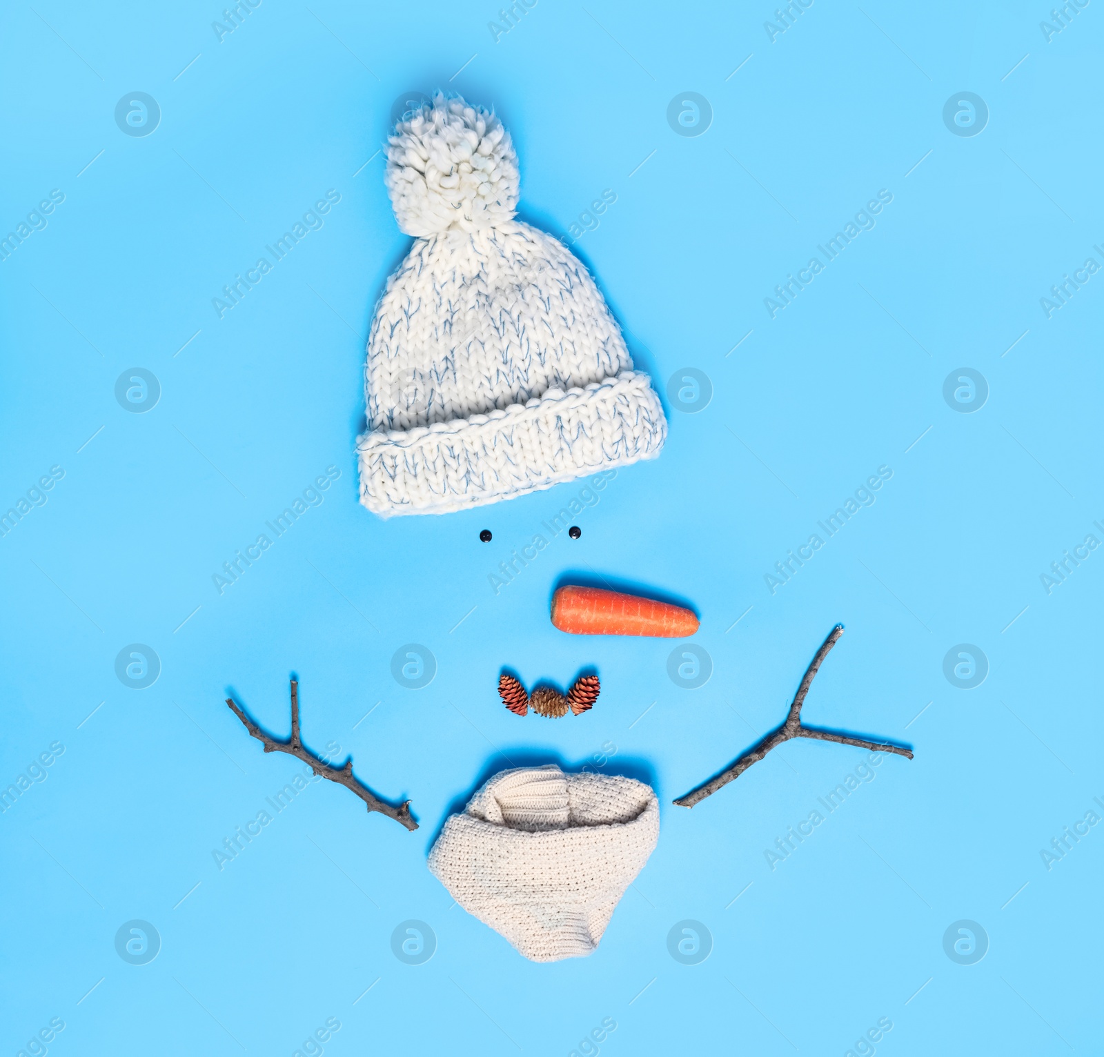 Photo of Creative snowman shape made of different items on light blue background, flat lay