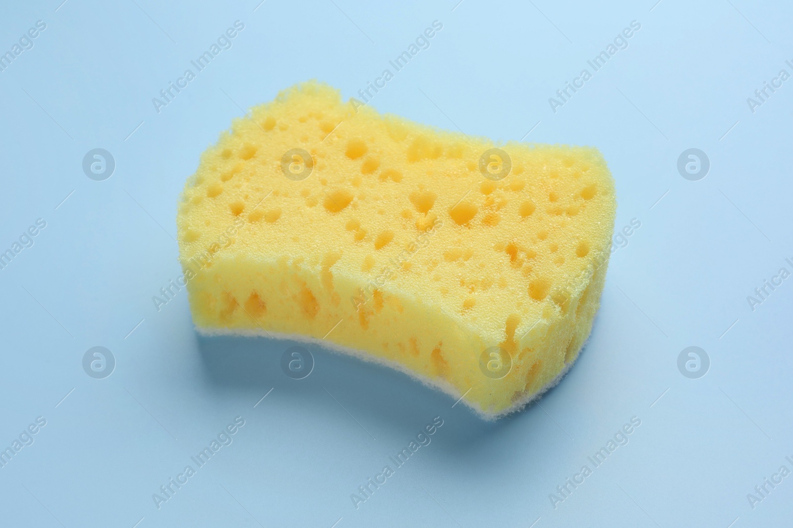 Photo of New yellow sponge on light blue background