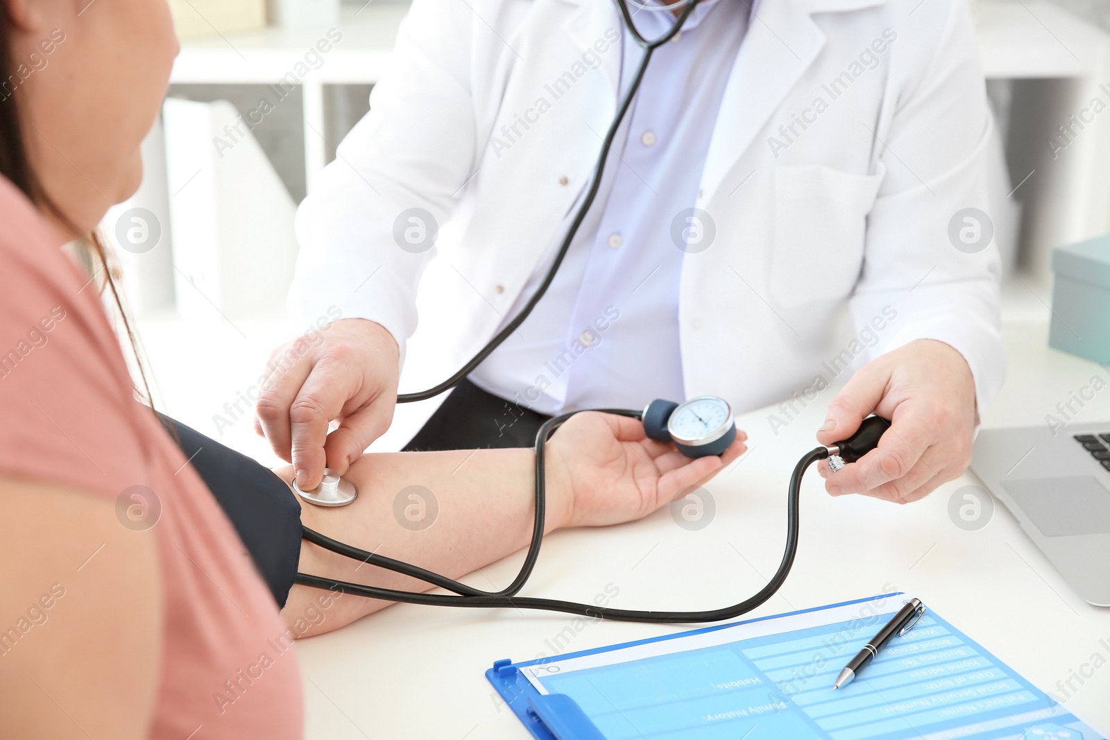 Photo of Doctor measuring blood pressure of overweight woman in clinic