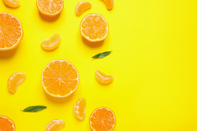 Photo of Flat lay composition with halves of fresh ripe tangerines and leaves on yellow background, space for text. Citrus fruit
