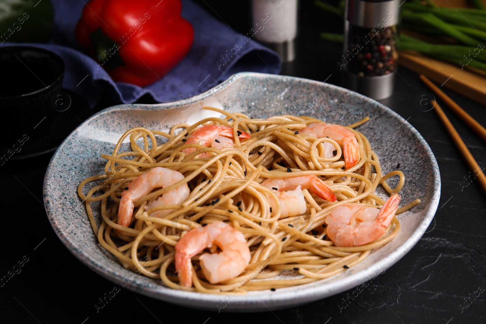 Photo of Tasty buckwheat noodles with shrimps served on black table