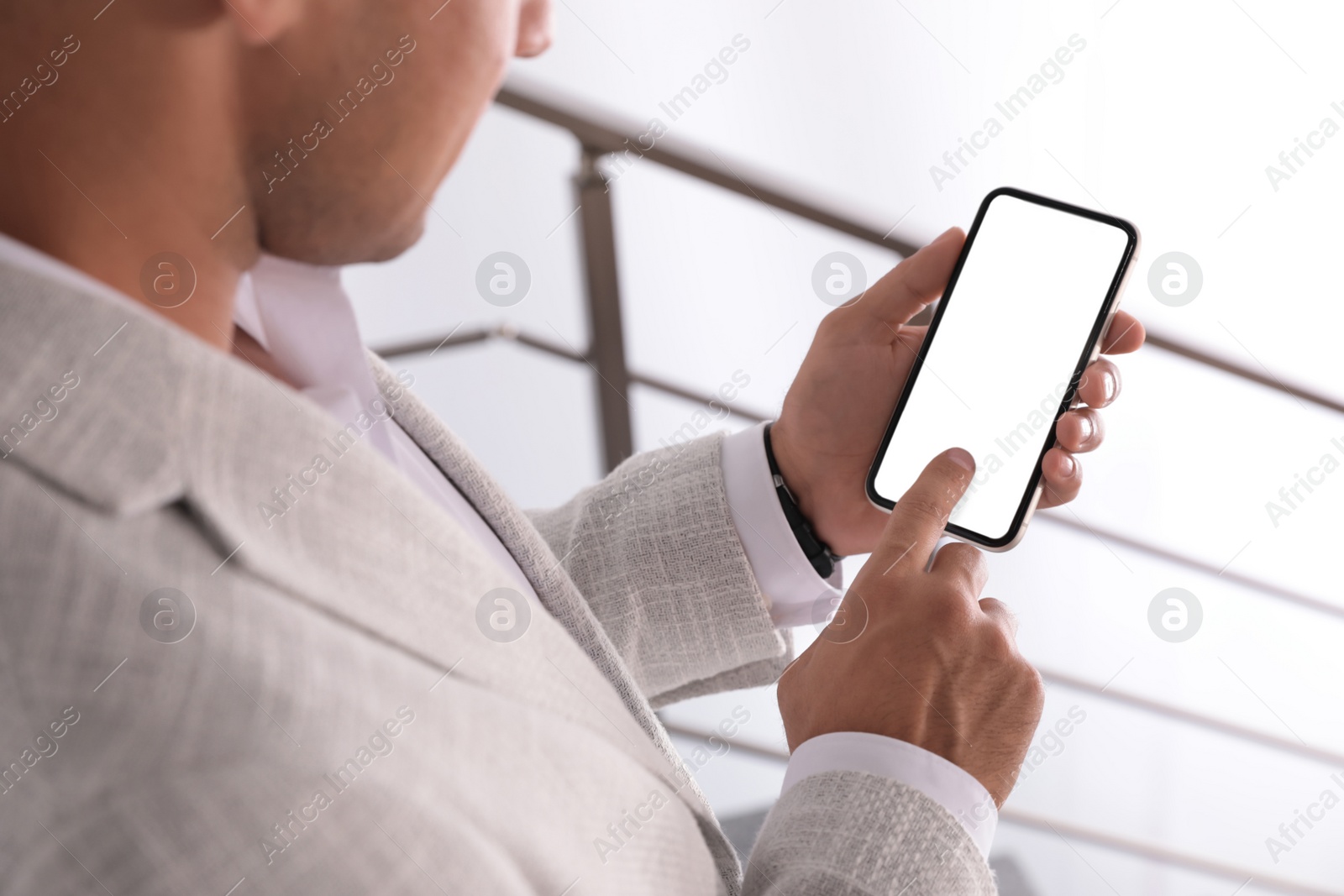 Photo of Man using mobile phone with empty screen indoors, closeup