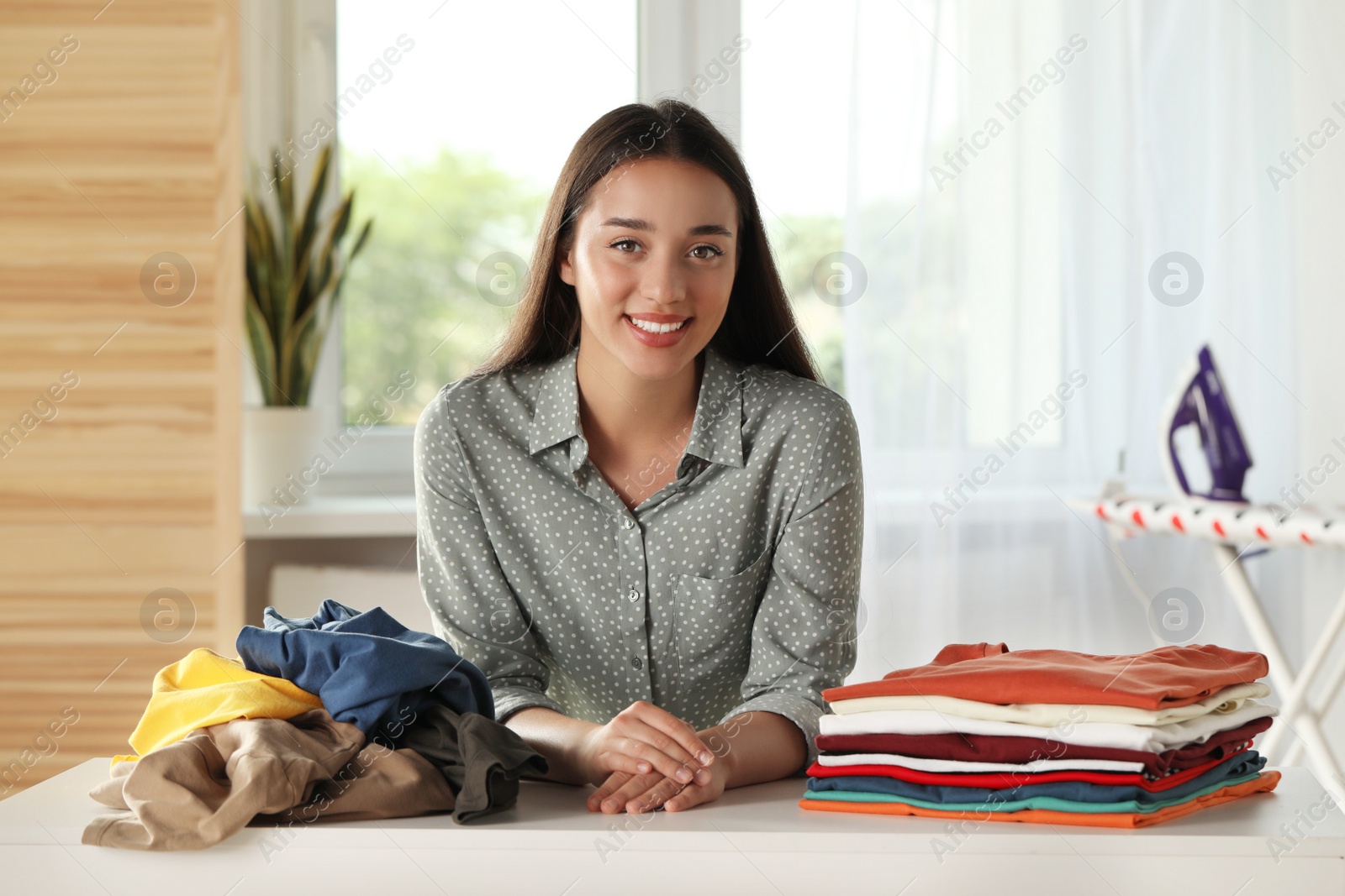 Photo of Young woman at table with different clothes indoors