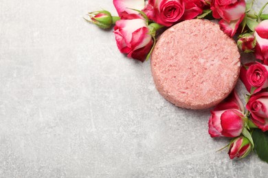 Photo of Solid shampoo bar and roses on light grey table, flat lay. Space for text