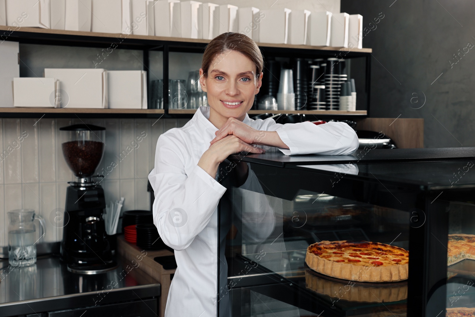 Photo of Professional baker near showcase with pastries in store