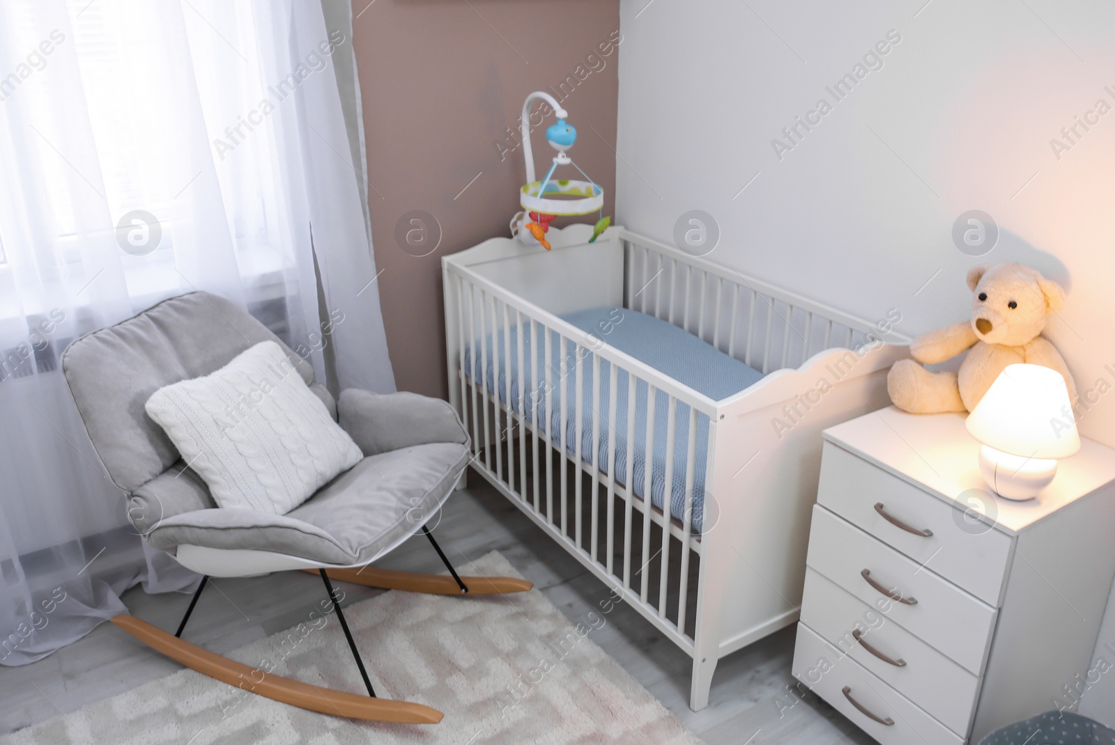 Photo of Cozy baby room interior with crib and rocking chair