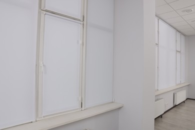 Photo of Windows covered with white roller blinds indoors