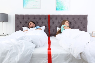 Photo of Upset couple with relationship problems lying separately in bed at home