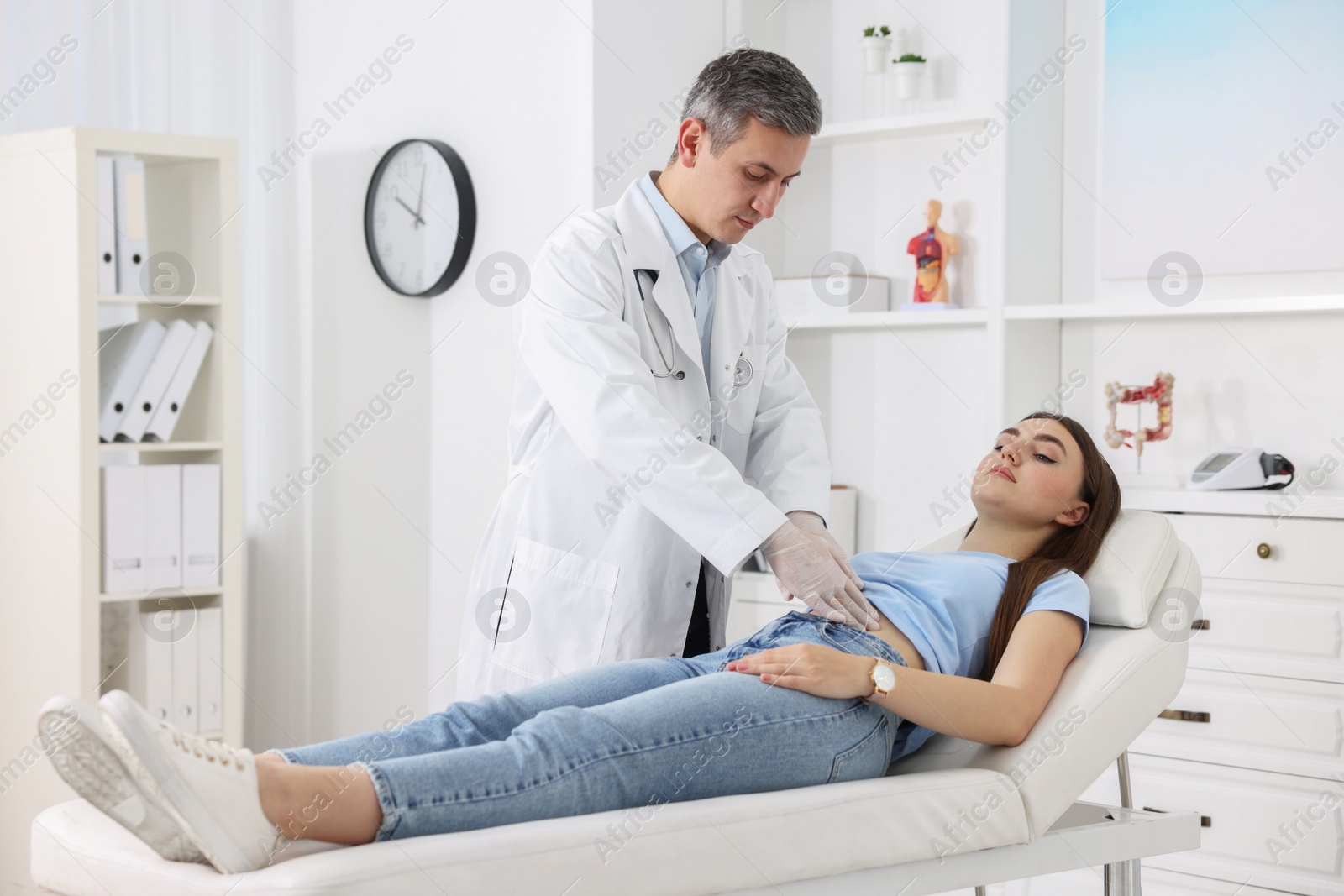 Photo of Gastroenterologist examining patient with stomach pain on couch in clinic