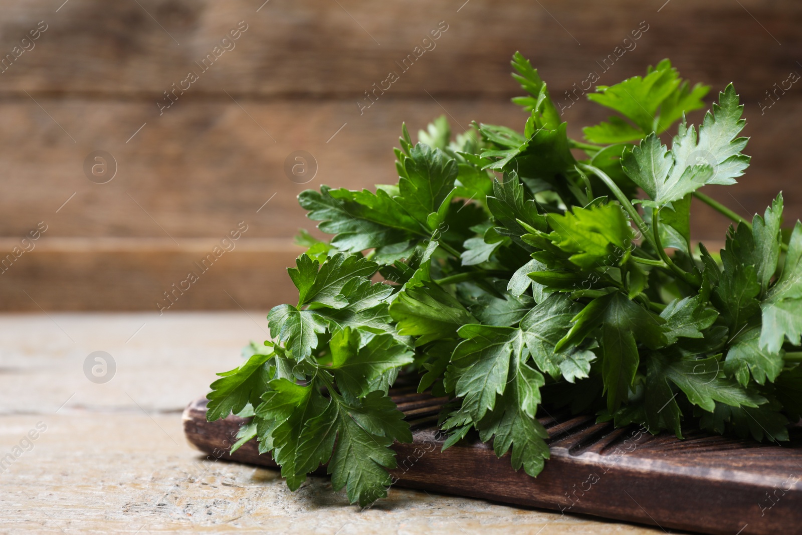 Photo of Board with fresh green parsley on wooden table, closeup