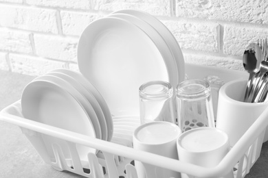 Photo of Dish drainer with clean plates on table, closeup