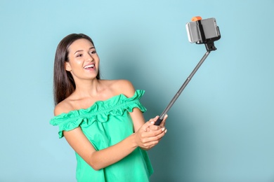 Young beautiful woman taking selfie against color background