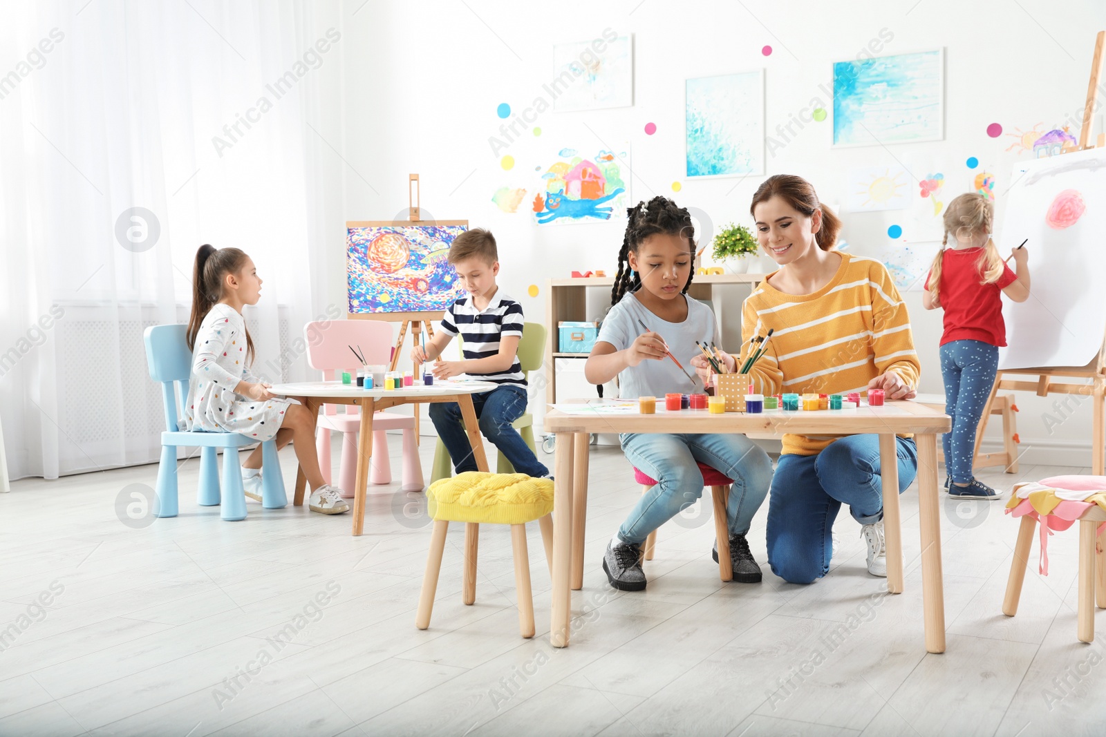 Photo of Children with female teacher at painting lesson indoors