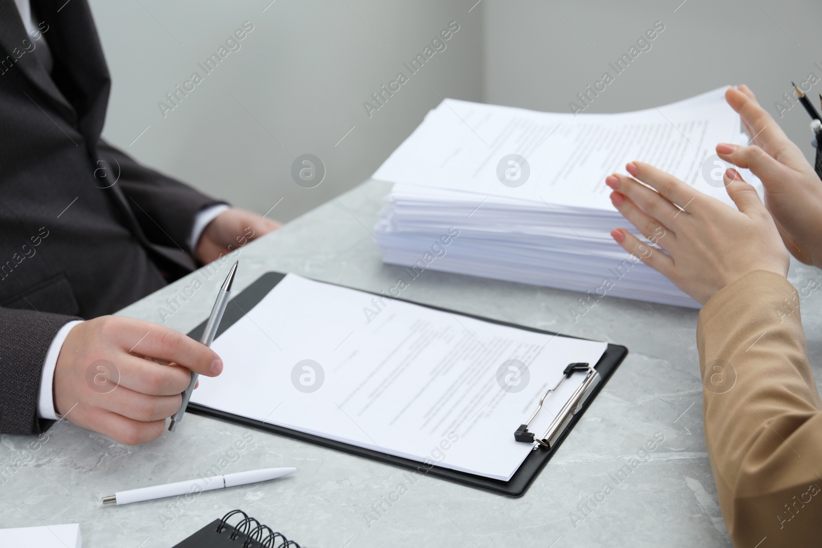 Photo of Man and woman discussing documents at table in office, closeup
