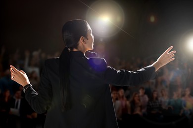 Image of Motivational speaker with headset performing on stage, back view
