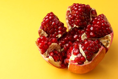 Photo of Cut fresh pomegranate on yellow background, closeup. Space for text