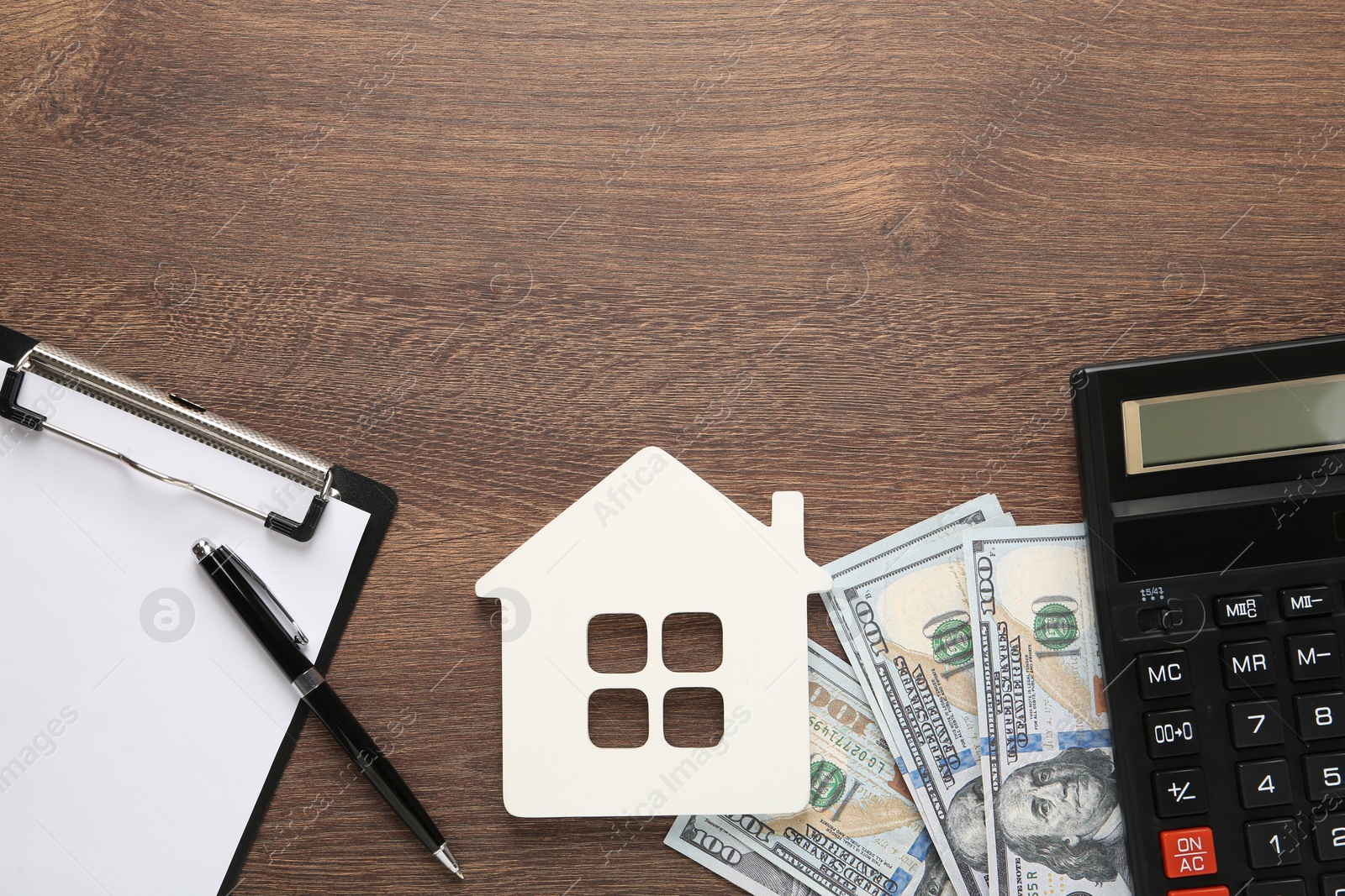 Photo of Mortgage concept. House model, clipboard, calculator and money on wooden table, flat lay with space for text