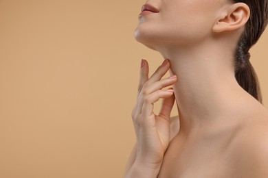 Photo of Woman touching her neck on beige background, closeup. Space for text