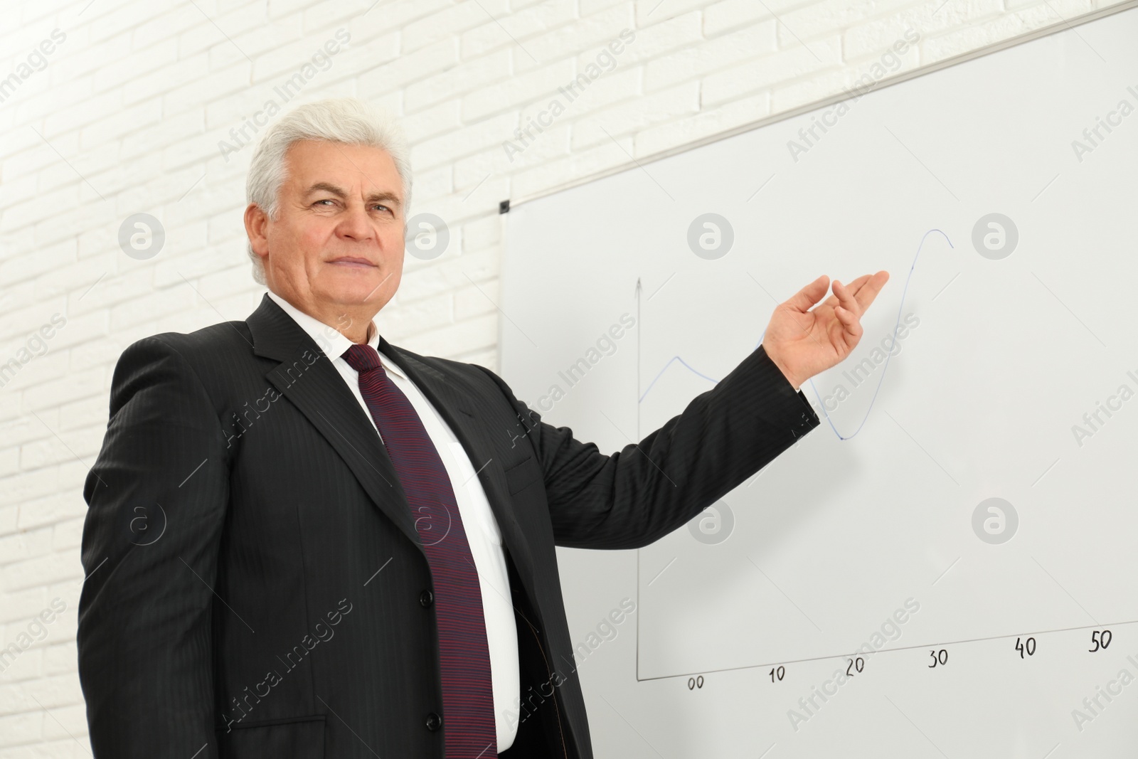 Photo of Senior business trainer near whiteboard in office