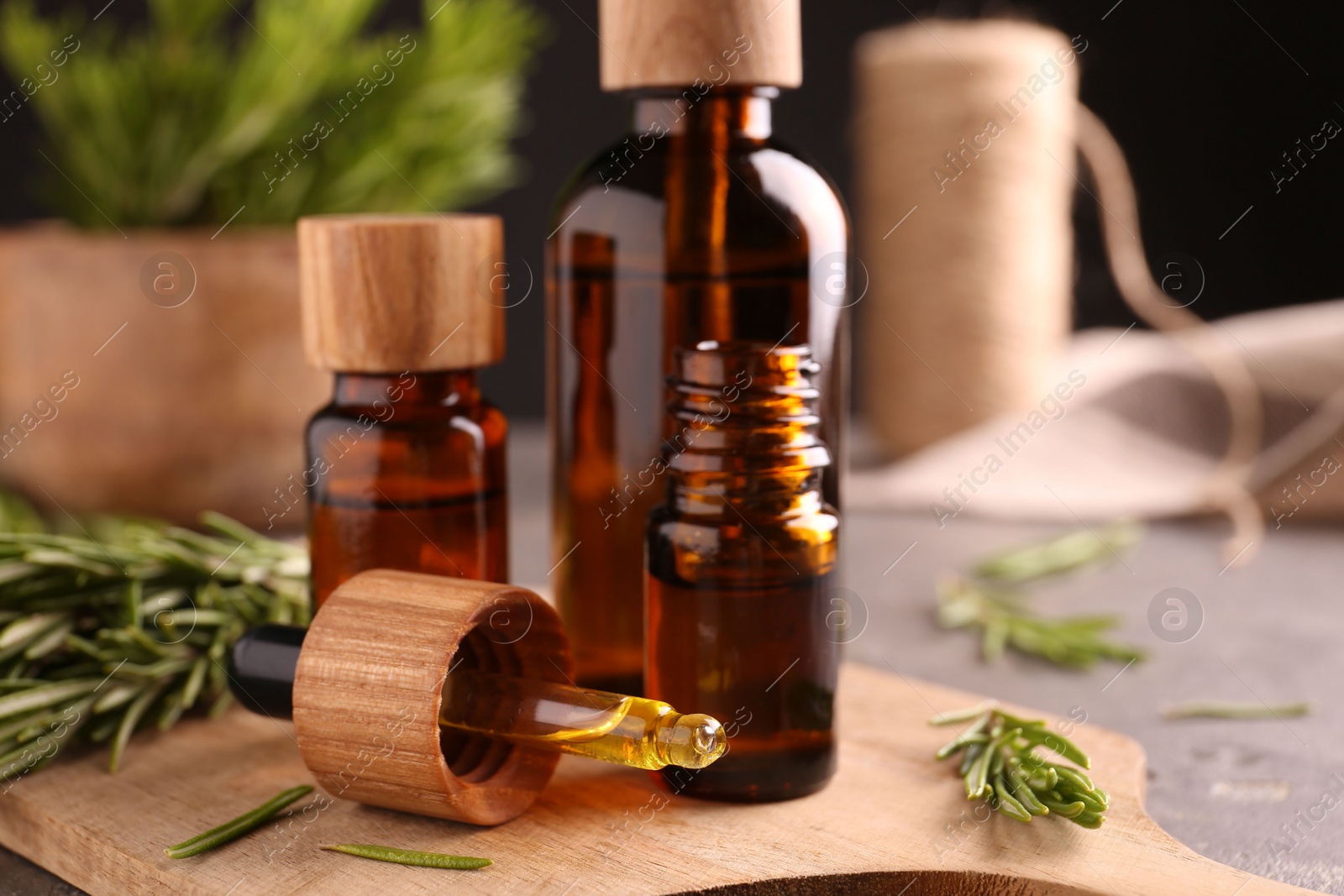 Photo of Essential oil in bottles, dropper and rosemary on table, closeup