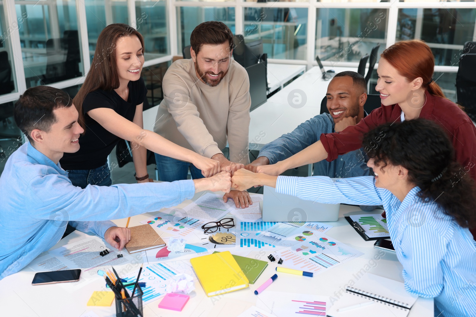 Photo of Team of employees joining hands in office. Startup project