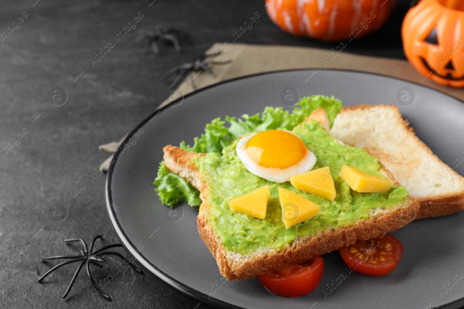 Photo of Halloween themed breakfast served on black table, closeup. Tasty sandwich with fried egg