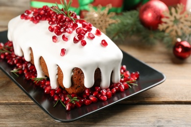 Photo of Traditional classic Christmas cake decorated with pomegranate seeds and rosemary on wooden table