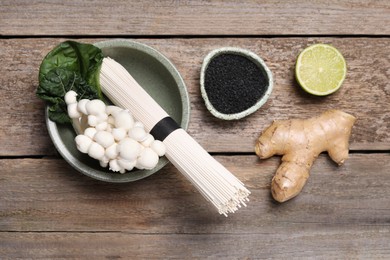 Photo of Cooking delicious ramen soup. Different ingredients on wooden table, flat lay