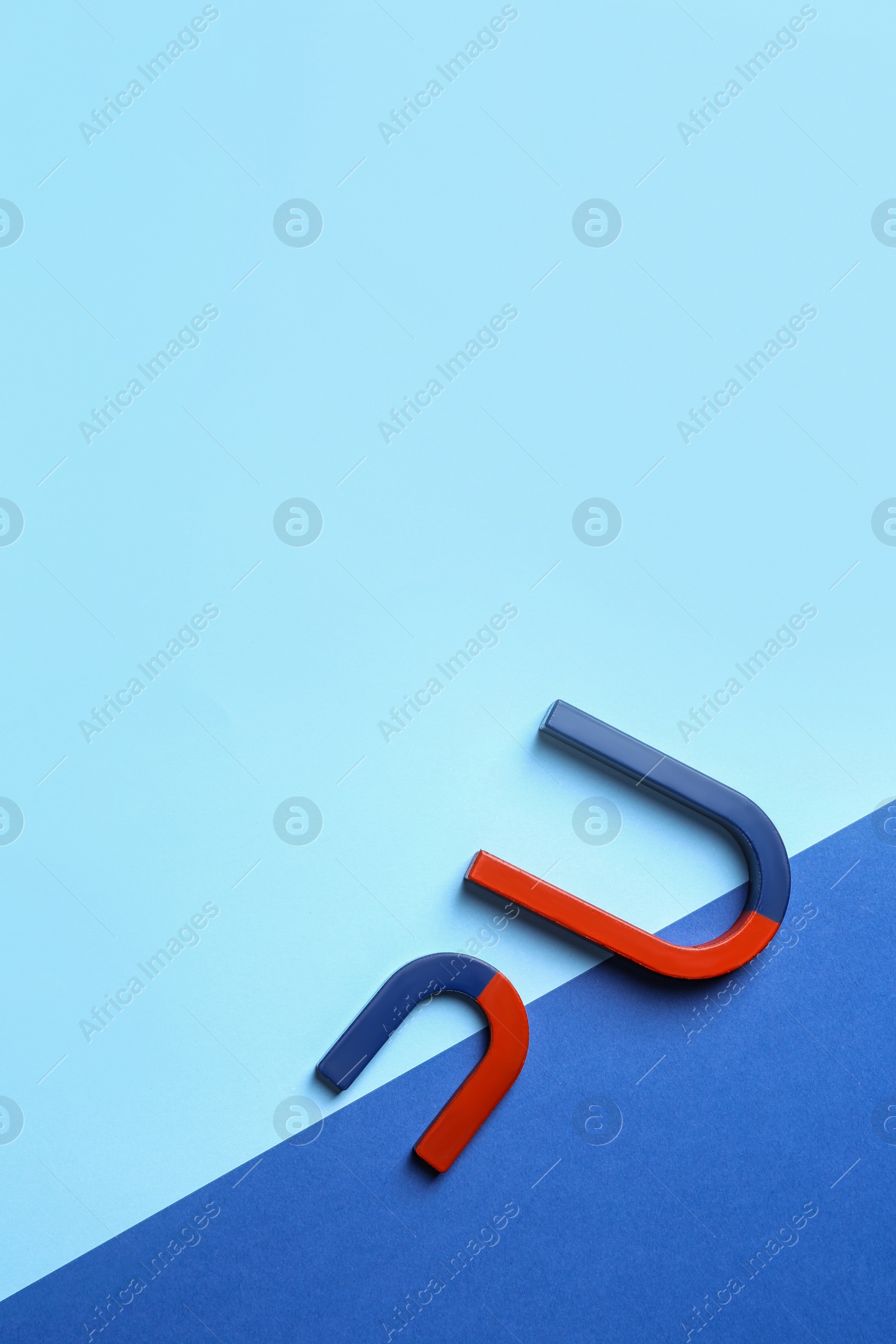 Photo of Red and blue horseshoe magnets on color background, flat lay. Space for text